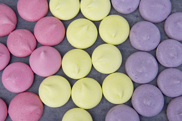 Pink, green and purple meringues on a grey background