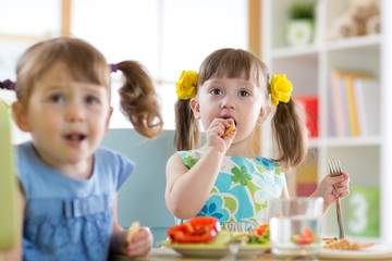 Children toddlers eating healthy food and cookie at kindergarten