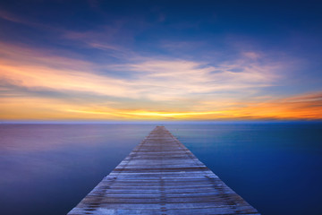 Fototapeta na wymiar Wooden bridge on sea at sunset