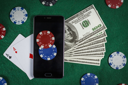 Poker chips, phone and cards on the green table