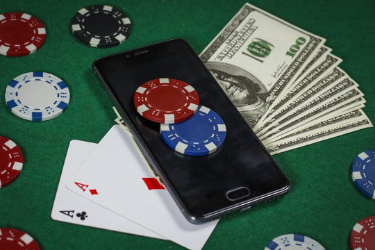 Poker chips, phone and cards on the green table