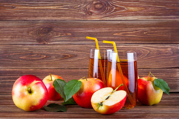 Fresh organic farm apple juice in glass with raw whole and sliced red apples on woody background