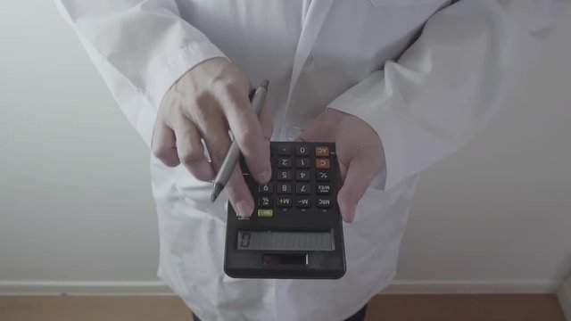 Healthcare costs and fees concept.Hand of smart doctor used a calculator for medical costs in modern hospital