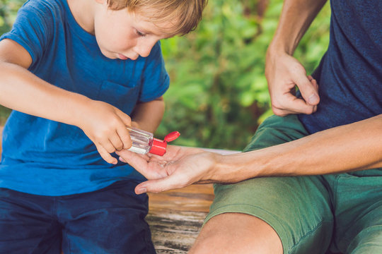 Father and son using wash hand sanitizer gel in the park before a snack