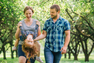 Cute young happy family having fun in the park. Little girl with parents outdoors. Mother father and daughter.