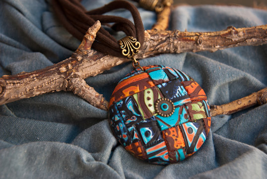 Unique colorful pendant in ethnic style. Background with jewelry. Handmade jewelry of polymer clay.