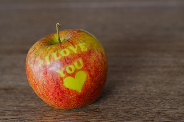 Red apple with text Ilove you lying on the wooden table background