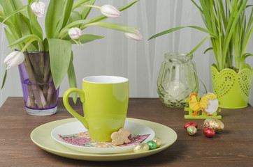 Easter tree and flowers with chocolate eggs on a wooden table