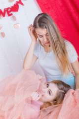 Two cute long-haired girlfriends in dresses sit and cuddle against