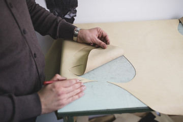 Close up of a male shoemaker working with leather textile at his workshop.