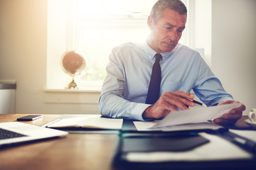 Businessman sitting at an office desk examining paperwork