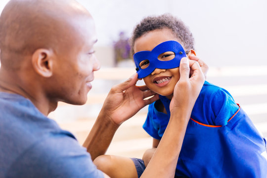 Happy smiling African American son being supported and helped by supportive father for little adventure and protection.