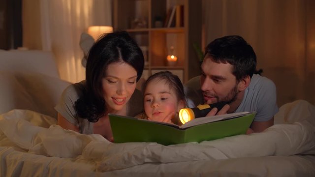 happy family reading book in bed at home