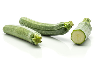 Two green zucchini with one sliced half isolated on white background long raw courgettes.