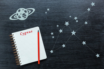 Zodiacal star, constellations Cygnus on a black background with a notepad and pencil.