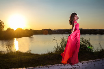 Beautiful girl in a red dress on sunset