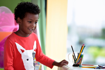 African American boy enjoy make homework in the international kindergarten library.