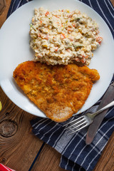 Fried pork chop in breadcrumbs, served with vegetable salad.