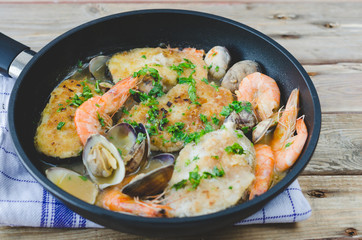 Hake with prawns and clams in frying pan.
