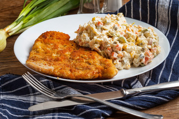 Fried pork chop in breadcrumbs, served with vegetable salad.