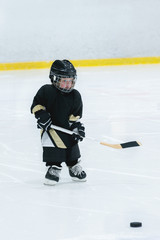Obraz premium Little cute blond girl plays hockey in full equipment on the ice arena