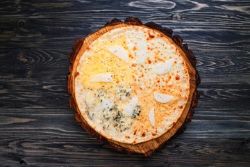 Delicious quattro formaggi cheese pizza with pear on wood, top view. Italian restaurant concept