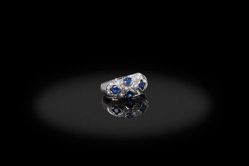 Silver precious ring female with diamonds and sapphire on black background. Good material for design jewelery.