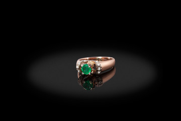 Yello gold precious ring female with diamonds and big emerald on black background. Good material for design jewelery.