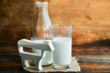 milk bottle, glass of milk, a figure of a cow the concept of a village power, farm-fresh products on a natural wooden background