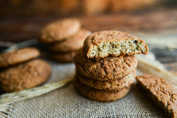 fresh homemade oatmeal cookies on wooden background with spikes of oats