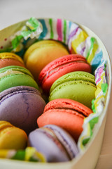 colorful macaroons in a gift box with a bright paper on a light background