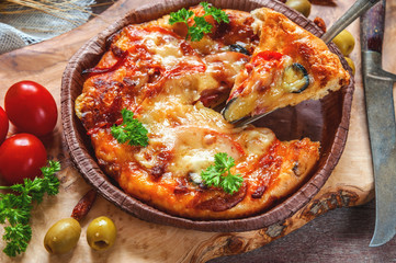 Round sausage pizza Margherita on a beautiful natural blackboard of olive . Selective focus.