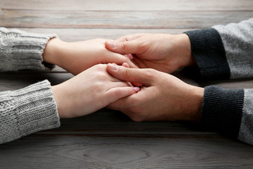 Female and male hand holding each other on grey background