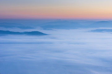The top of the ridge in the clouds. Deep perspective. Sunset in the mountains.