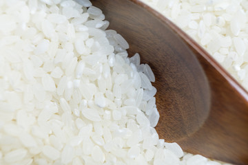 Photo of raw rice grains that are typed with a wooden spoon.