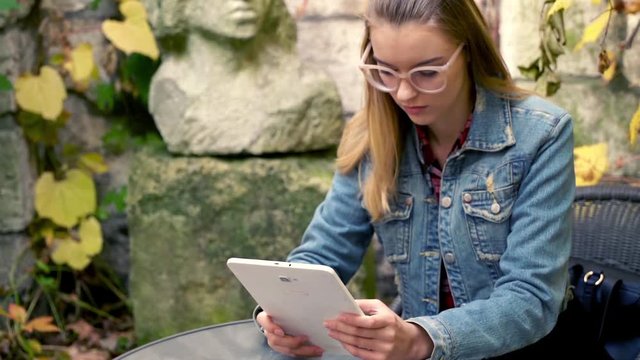 Young, pretty woman using tablet while sitting in the garden
