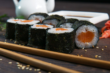 Sushi rolls served on a wooden plate in a restaurant. Sushi rolls and caviar on black wooden table. Japanese food.
