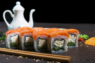 Sushi rolls served on a wooden plate in a restaurant. Sushi rolls and caviar on black wooden table. Japanese food.