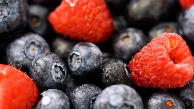 Fresh blueberry and raspberries slow macro pan with water droplets on the fresh fruit.