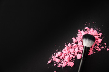 makeup brush with pink blush on black background