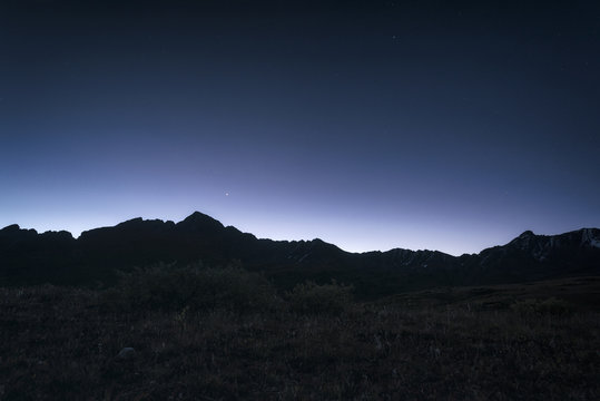 View of silhouette mountain against blue sky at night