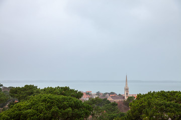 Fototapeta na wymiar Aerial view of Arcachon, France, during a storm on a rainy day, with Notre Dame basilica in front. Located in Arcachon bay, the city is one of most touristic spots of the Atlantic coast in France