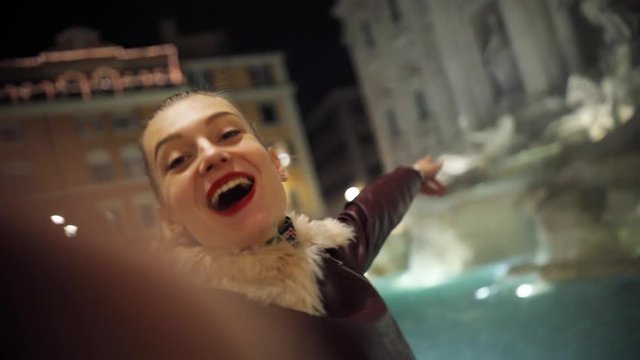 Happy young girl with red lips taking selfie smiling waving his hands night city woman winter technology female phone smartphone street cellphone romantic italy rome portait close up attractive