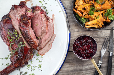 Marinated sliced barbecue aged leg of venison with chanterelles and cherry sauce as top view on...