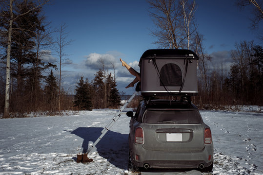 Low section of woman sitting in roof tent on car