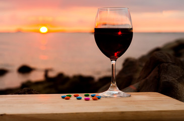a glass of red wine by the beach during sunset. selective focus.
