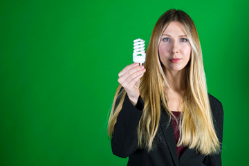 Serious young business woman holding a light bulb on a green background. Portrait of a successful model