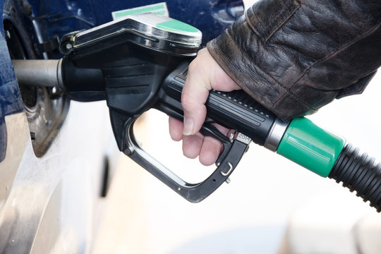 hand holds a nozzle to refuel a car with diesel fuel at the gasoline station
