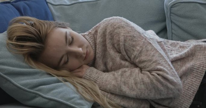 Young sleepy woman falling down on sofa at home.