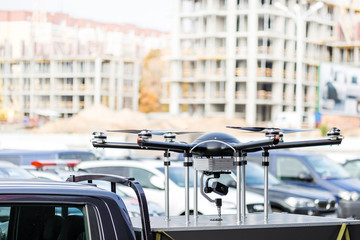 Big custom made drone over picup truck trunk.  Heavy UAV hexacopter
with construction site on the background. Commercial aerial photo and video concept